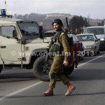 An Israeli soldier walks in front of a military vehicle near the scene of a shooting in al-Arroub refugee camp near Hebron