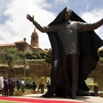 People stand near the 9-metre bronze statue of Nelson Mandela as it is unveiled as part of the Day of Reconciliation Celebrations at the Union Buildings in Pretoria