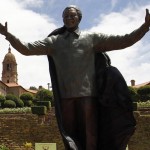 People stand near the 9-metre bronze statue of Nelson Mandela as it is unveiled as part of the Day of Reconciliation Celebrations at the Union Buildings in Pretoria